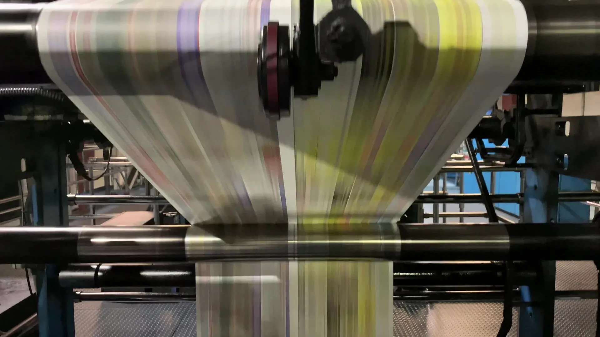 A newspaper press running at speed, paper flying through the rollers
